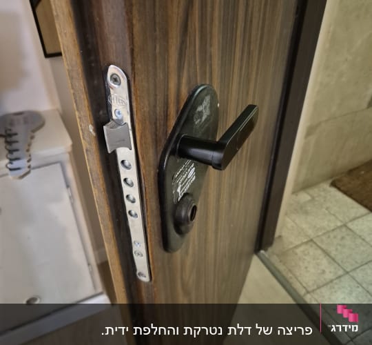 מנעול דלת עם ידית שחורה על דלת עץ